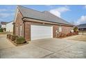 Attached brick garage with white door and landscaping at 573 Church St, Locust, NC 28097