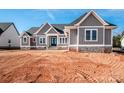 New home with gray siding, stone accents, a double-door entry, and a manicured yard on a sunny day at 6098 Ballard Rd, Denver, NC 28037