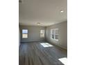 Sunlit living room with laminate flooring, neutral walls, three large windows, and recessed lighting at 6332 Honor Ave, Midland, NC 28107