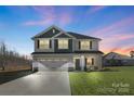 Two story home with two-car garage, a welcoming porch, and well-maintained landscaping at twilight at 821 Bethesda Rd, Statesville, NC 28677