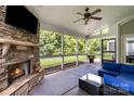 Relaxing screened-in porch featuring a stone fireplace, comfortable seating, and views of the lush backyard at 2201 Bluebell Way, Tega Cay, SC 29708