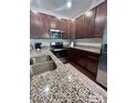 Modern kitchen featuring stainless steel appliances, granite countertops and dark wood cabinetry at 7420 Sienna Heights Pl, Charlotte, NC 28213