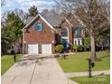 Classic two-story brick home featuring a two-car garage, a well-maintained lawn, and traditional architectural charm at 11911 Farnborough Rd, Huntersville, NC 28078