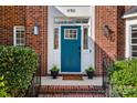 Inviting entryway featuring a stylish blue front door, brick steps, potted plants, and decorative outdoor lighting at 11911 Farnborough Rd, Huntersville, NC 28078