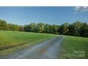 Gravel driveway leading to the property, surrounded by green field and lush trees at 4816 Zion Church Rd, Concord, NC 28025
