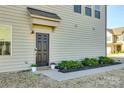 Inviting front entrance with a dark door, manicured shrubs, and a welcoming doormat on a sunny day at 5373 Orchid Bloom Dr, Indian Land, SC 29707