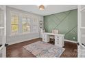 Home office with green accent wall, built-in shelving, and hardwood floors at 9635 Andres Duany Dr, Huntersville, NC 28078