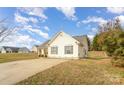 Side view of a light yellow home with a well-kept lawn and a long driveway at 101 Arbridge Ct, Mount Holly, NC 28120