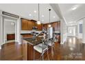 Spacious kitchen featuring dark cabinetry, granite countertops, an island with seating, and hardwood floors at 10120 Garman Hill Dr, Charlotte, NC 28214