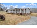 Gray mobile home with wrap-around porch and gravel driveway at 15918 Big Bear Rd, Albemarle, NC 28001