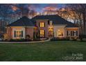 Charming brick home with manicured lawn, mature landscaping, and inviting front entrance at dusk at 162 Wild Harbor Rd, Mooresville, NC 28117