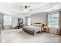 Spacious bedroom with a tray ceiling, neutral color scheme, and large windows for natural light at 2727 Cypress Oak Ln, Gastonia, NC 28056