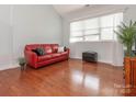 Bright living room featuring hardwood floors, large windows, and a comfortable red leather sofa at 3867 Azalea Trl, Denver, NC 28037