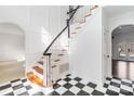 Elegant foyer features black and white tile, a staircase with wood treads, and white walls with wainscoting at 4001 Carmel Acres Dr, Charlotte, NC 28226