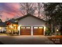 A two-car garage at dusk with paneled doors, with additional lighting and landscaping at 10 Catawba Ridge Ct, Clover, SC 29710