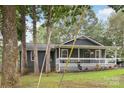 View of home exterior with covered front porch, gray siding, and a gravel driveway at 107 Deese Ct, Indian Trail, NC 28079
