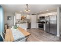 Bright kitchen with stainless steel appliances, white cabinets, and a rustic wooden dining table at 1140 Roberts St, China Grove, NC 28023