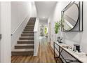 Bright entryway featuring a staircase, modern decor, wood floors, and an inviting view into the living area at 122 I K Beatty St, Charlotte, NC 28214