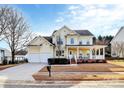Traditional yellow home with a spacious porch, a manicured lawn, and an attached two-car garage at 15313 Wedgewood Commons Dr, Charlotte, NC 28277