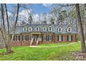 Charming brick home with a blue door, dormer windows, black shutters, and a beautifully landscaped lawn at 2305 Beechwood Dr, Waxhaw, NC 28173