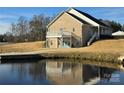 Rear exterior view of brick home with a walkout basement and pond at 2510 Lentz Rd, China Grove, NC 28023