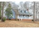 Charming blue home with a brick foundation and covered front porch surrounded by mature trees at 622 Oakdale Dr, Statesville, NC 28677