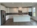 Modern white kitchen with stainless steel appliances, island, and gray backsplash at 7120 Wayfarer Dr # 0079, Charlotte, NC 28269