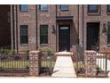 Brick townhome with a black front door, small garden area, and a black iron fence at 216 Gilead Rd, Huntersville, NC 28078