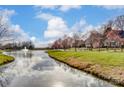 Scenic view of the community pond and walking trail, lined with trees in a residential neighborhood at 561 Ambergate Nw Pl, Concord, NC 28027