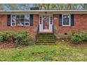 Charming red brick home featuring stairs leading up to the entry door at 725 Plantation Rd, Lancaster, SC 29720