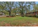 Well-maintained front yard with mature trees and lush greenery surrounding a classic brick home at 725 Plantation Rd, Lancaster, SC 29720