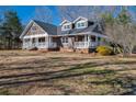 Inviting two-story home featuring a wide porch, surrounded by trees on a sunny day at 3044 Old Church Rd, Gastonia, NC 28052