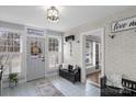 Inviting entryway with white brick accent wall, a bench, and plenty of natural light at 8478 Rocky River Rd, Harrisburg, NC 28075