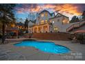 Beautiful backyard pool with a stone patio, string lights, outdoor seating, and lush landscaping for serene relaxation at 134 Wild Harbor Rd, Mooresville, NC 28117