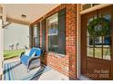 Close-up of a cozy front porch with a cushioned chair, brick accents, and decorative wreath at 162 Misty Woods Dr, Lake Wylie, SC 29710