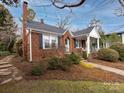 Brick home with stone walkway, mature trees, and a covered porch at 2121 Winter St, Charlotte, NC 28205