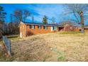 A single-story brick home on a sloped lot, featuring a side entrance and a partially fenced yard at 2745 33Rd Ne Ave, Hickory, NC 28601