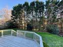 A gray wooden deck with white railing overlooks the lawn of a well-maintained back yard with trees at 9010 Scottsboro Dr, Huntersville, NC 28078