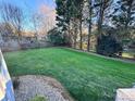 Large grassy backyard with a wooden fence, river rock landscaping, and mature trees providing privacy at 9010 Scottsboro Dr, Huntersville, NC 28078