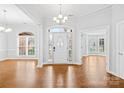 Spacious foyer with hardwood floors, decorative chandelier, and bright natural light through front door at 13501 Misty Dew Ct # 19, Charlotte, NC 28273