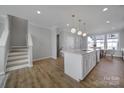 Bright kitchen island boasts pendant lighting and stainless steel appliances, connecting to the staircase at 14139 Loyola Ridge Dr, Charlotte, NC 28277