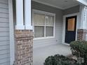 Inviting front porch with a dark blue door and brick columns at 14955 Alexander Place Dr, Huntersville, NC 28078