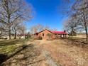 View of brick home with red roof and large yard featuring mature trees and outbuilding on a sunny day at 6523 Prospect Rd, Monroe, NC 28112