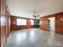 Spacious living room with wood paneling, ceiling fan, and open layout leading into the kitchen at 6523 Prospect Rd, Monroe, NC 28112