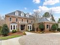 Stately brick home showcasing a circular driveway, mature trees, and architectural charm in daylight at 14407 Brick Church Ct, Charlotte, NC 28277