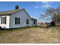 White one story house with a chimney and black framed windows and an expansive yard at 3186 Catawba St, Claremont, NC 28610