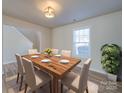 Well-lit dining room featuring wood floors, table set for six, and a plant near a window at 13410 Tartarian Ct, Charlotte, NC 28215