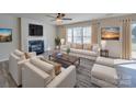 Bright living room with fireplace, ceiling fan, neutral tones, and large windows with stylish furnishings at 13410 Tartarian Ct, Charlotte, NC 28215