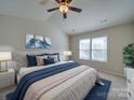 Cozy main bedroom showcasing a large bed, blue accents, wall art, and a window at 13410 Tartarian Ct, Charlotte, NC 28215