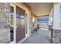 Covered front porch featuring stone accents, a stylish entry door, and a seating area at 4027 Wiltshire Ln, Indian Land, SC 29707